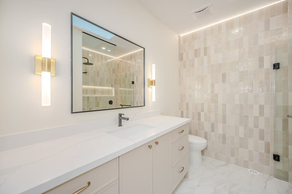 A bathroom with a large mirror , sink , toilet and shower.