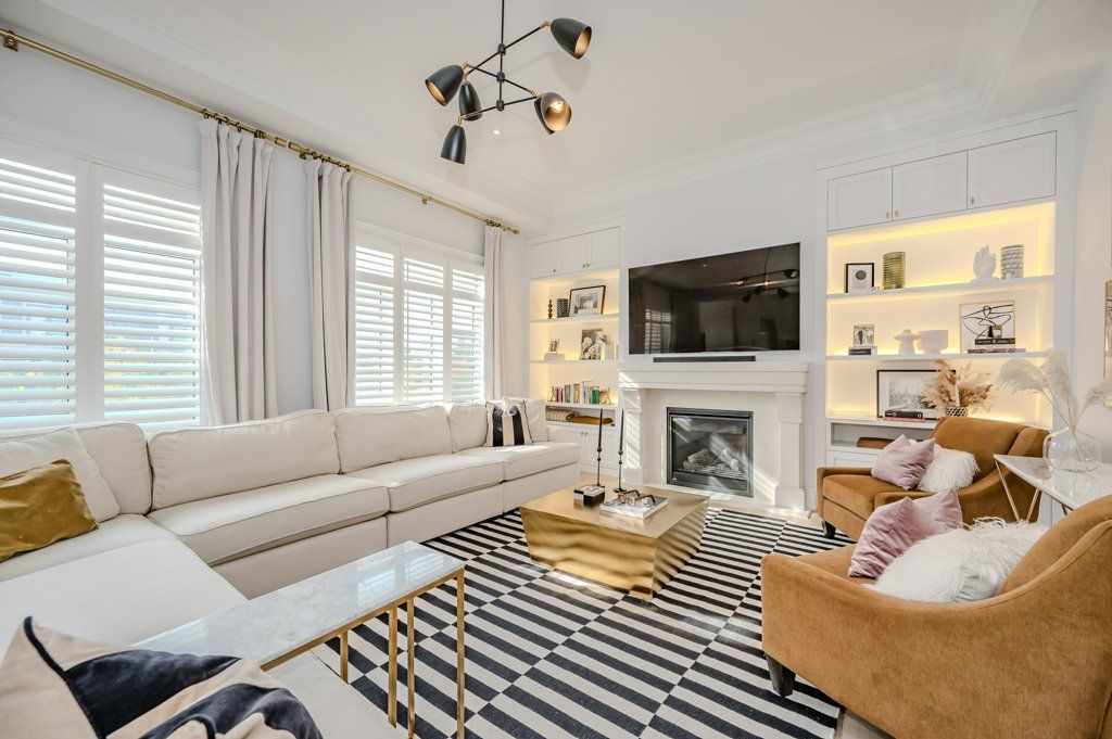 A living room with a couch , chairs , coffee table and television.