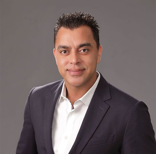 A man in a suit and white shirt is smiling for the camera.