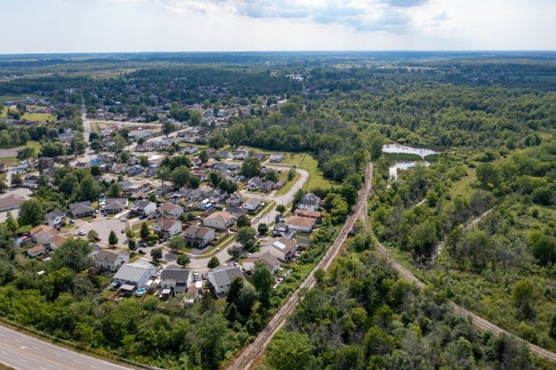 An aerial view of a residential area surrounded by trees and a train track.
