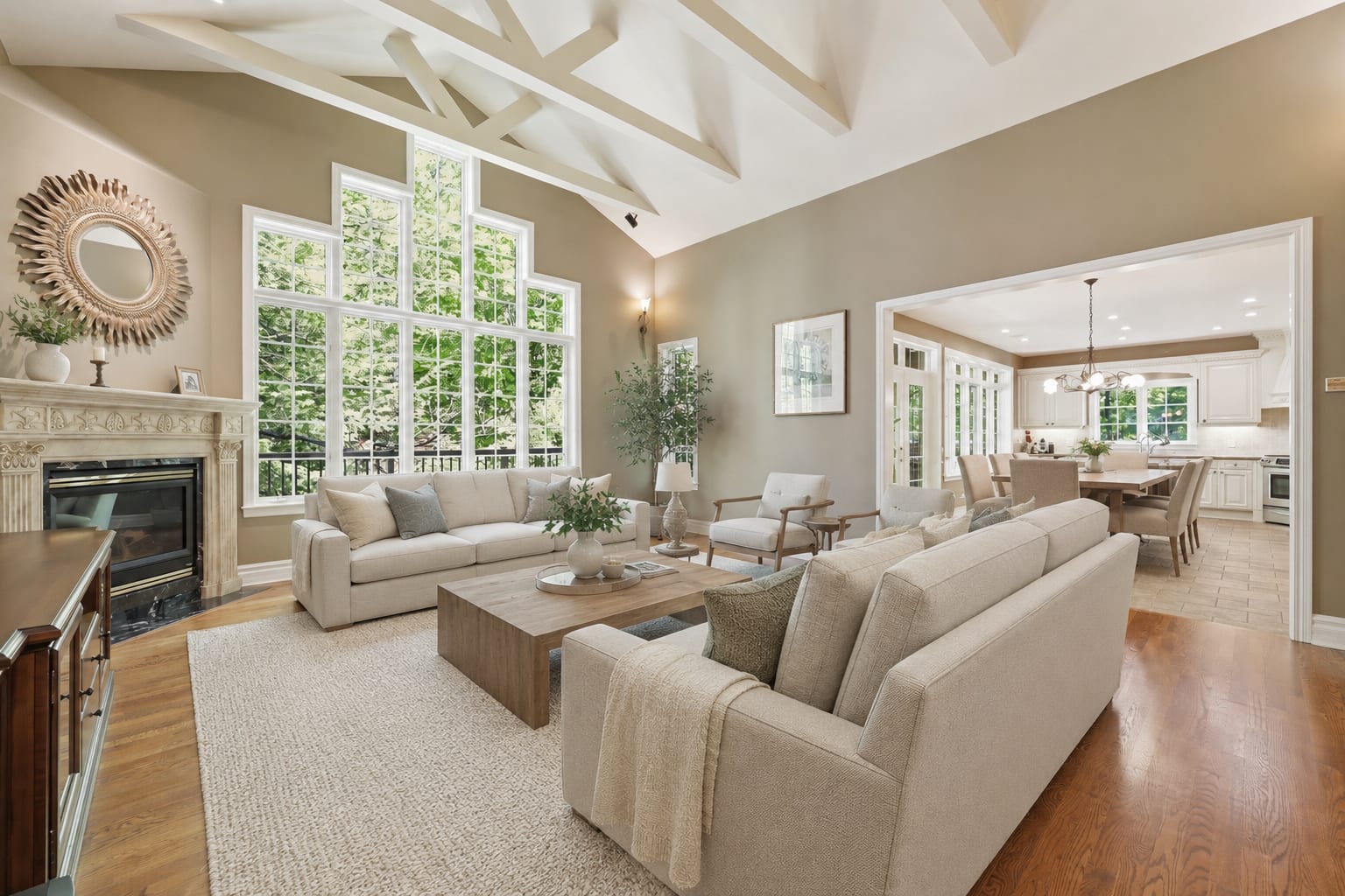 Spacious family room with a vaulted beamed ceiling, tall windows and a fireplace, open to the kitchen and dining area.