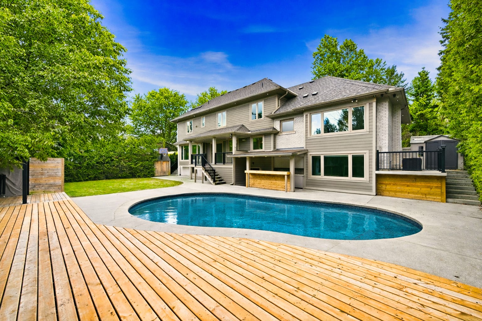 Backyard pool and cedar deck of a tree-lined Oakville property, marketed by the Dan Cooper Group.