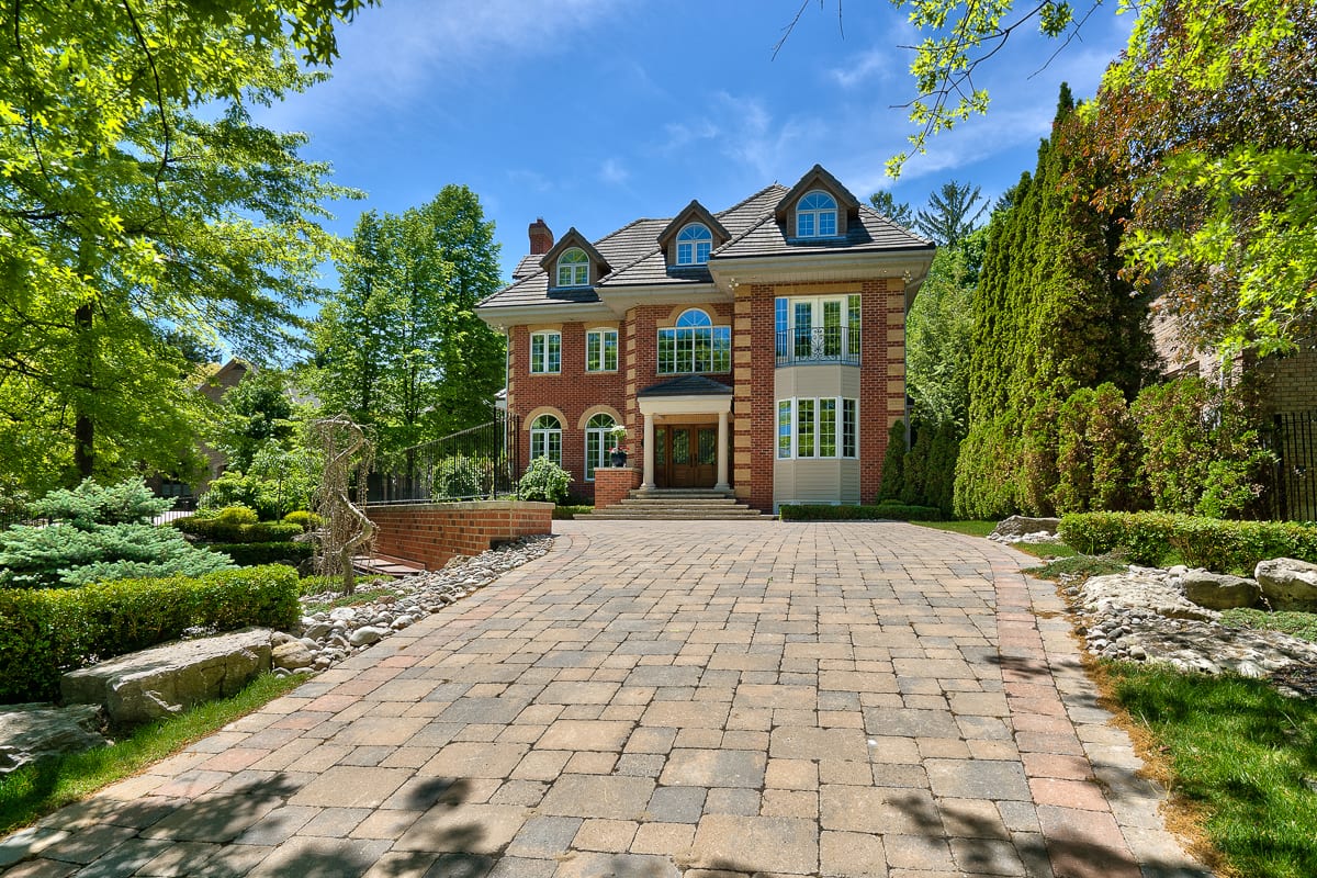 Brick estate home with a long interlock driveway and mature trees in Southeast Oakville, marketed by the Dan Cooper Group.
