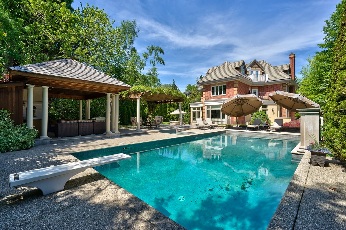 Backyard pool with a diving board and covered cabana at a Southeast Oakville estate, marketed by the Dan Cooper Group.