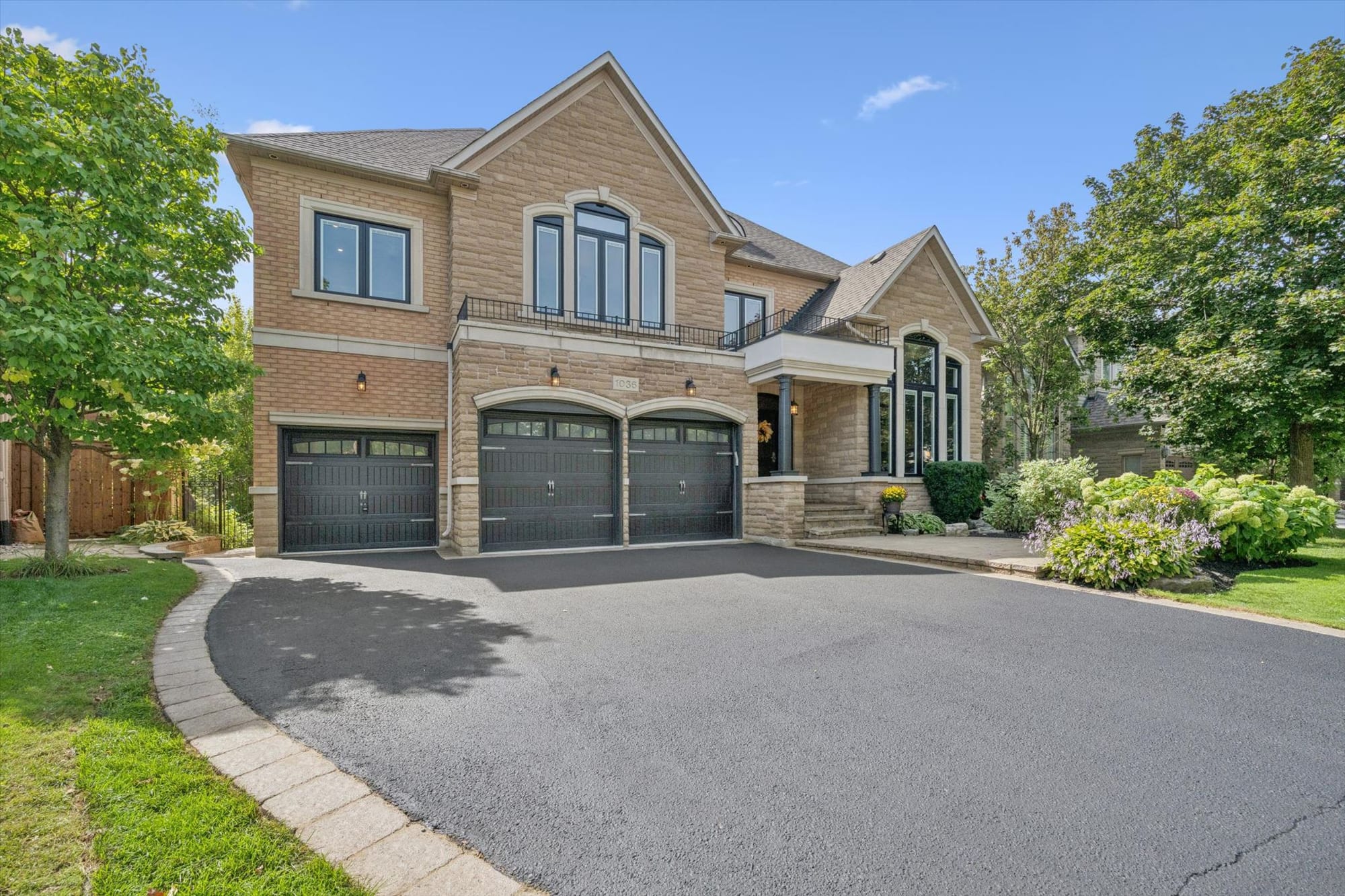 Brick-and-stone luxury home with a three-car garage in Oakville, marketed by the Dan Cooper Group.