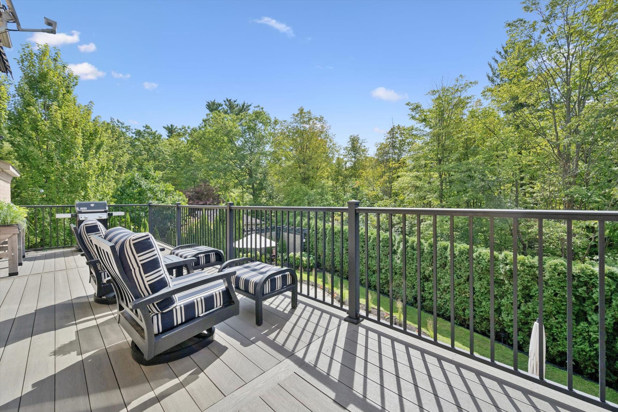 Upper deck with lounge seating overlooking mature trees at a luxury Oakville home, marketed by the Dan Cooper Group.