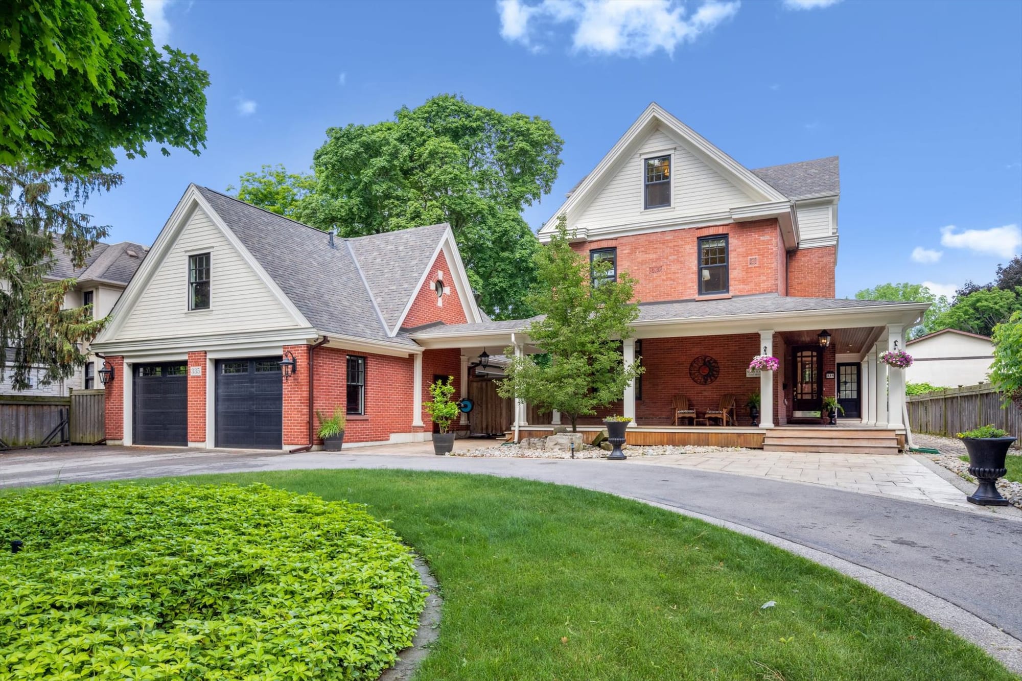 Red-brick Oakville home with a wraparound porch, detached garage and circular driveway, marketed by the Dan Cooper Group.