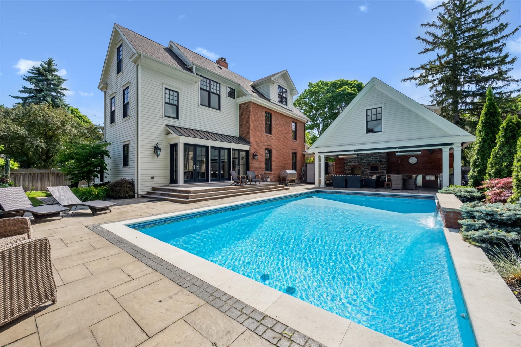 Backyard pool, stone patio and covered cabana behind a luxury Oakville home, marketed by the Dan Cooper Group.