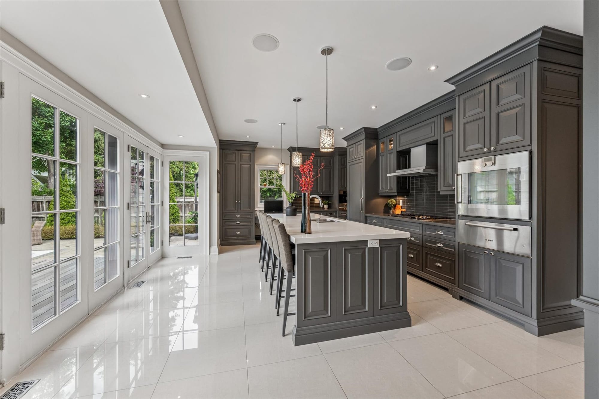 Custom kitchen with a long island and a wall of French doors in a luxury Oakville home, marketed by the Dan Cooper Group.