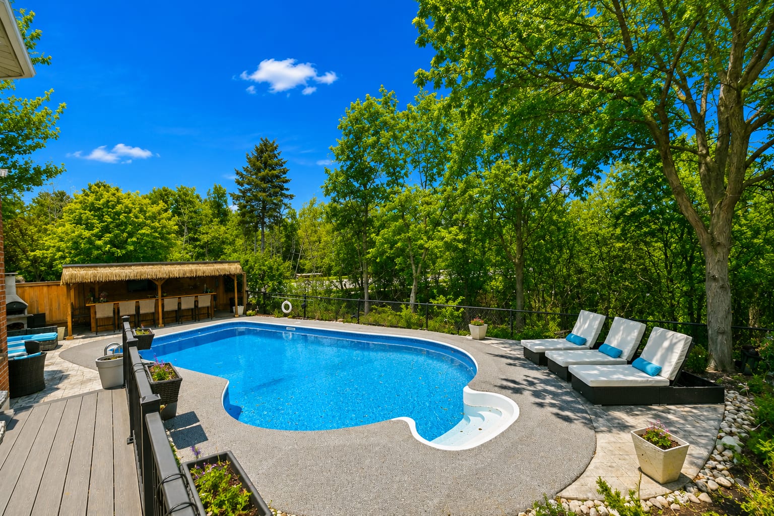 Backyard pool, loungers and tiki bar surrounded by mature trees at an Oakville home, marketed by the Dan Cooper Group.