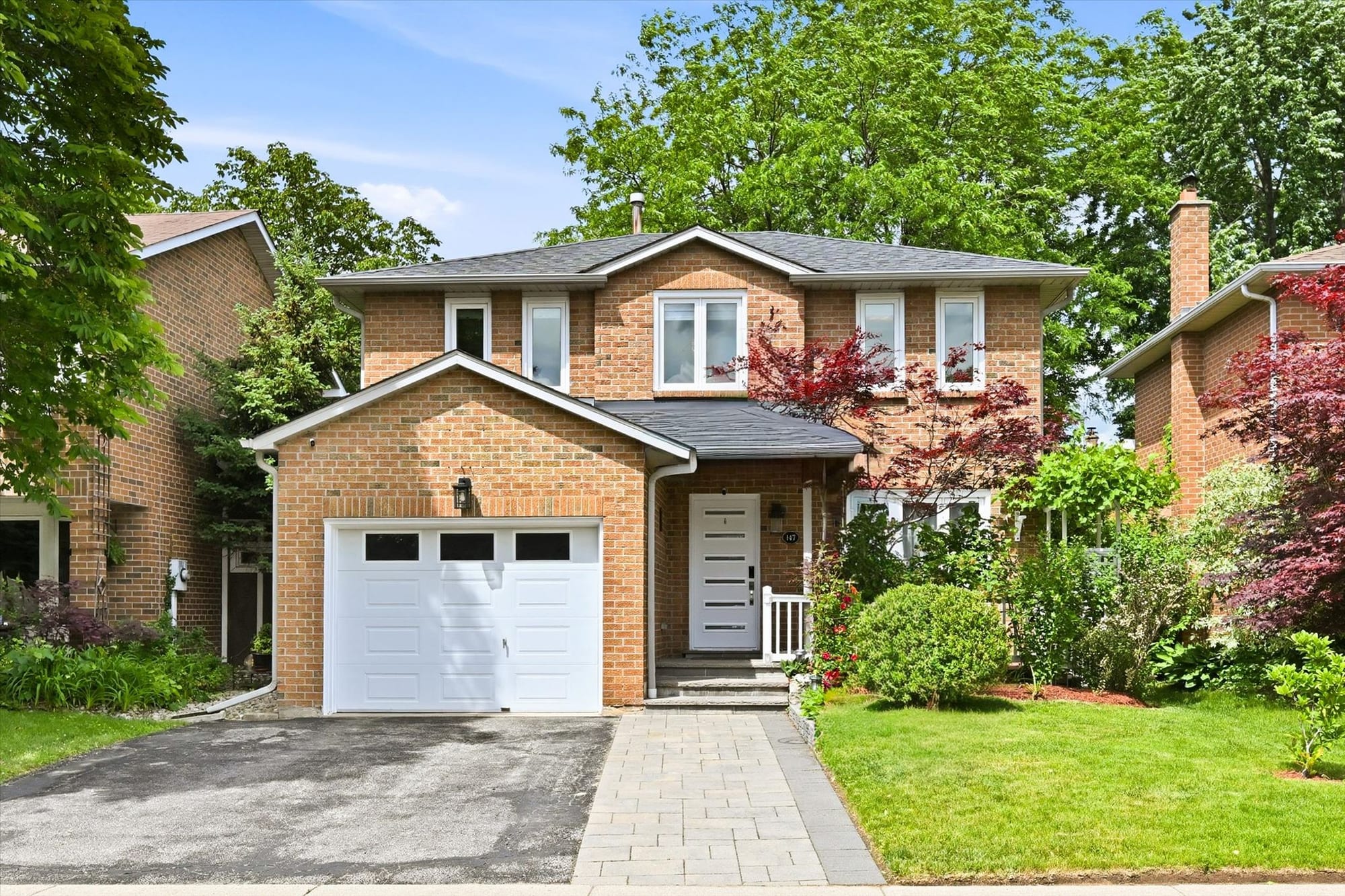 Two-storey brick home with a Japanese maple and landscaped front garden in Oakville, marketed by the Dan Cooper Group.