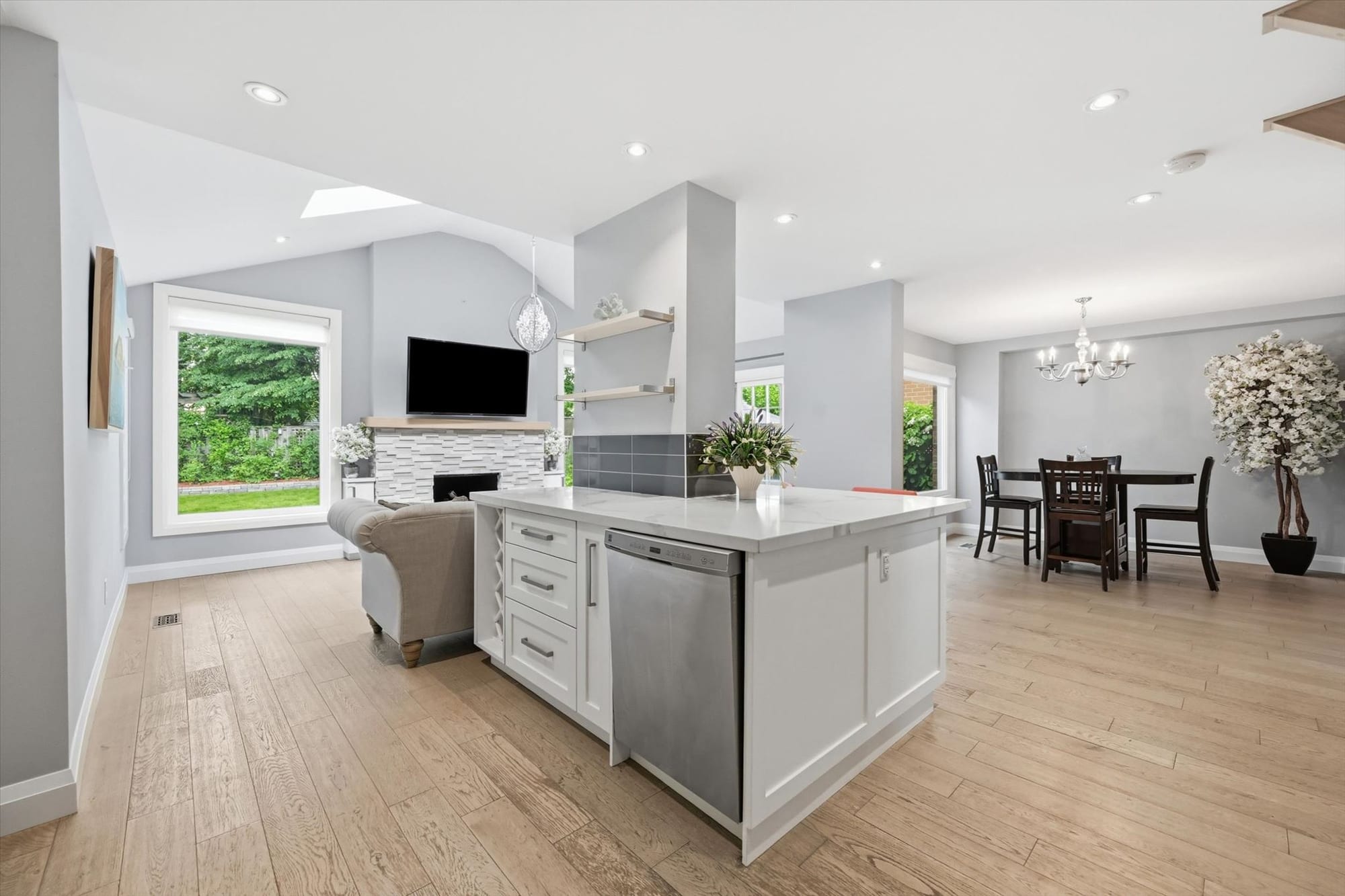 Open-concept kitchen, family room and dining area with a vaulted ceiling in a renovated Oakville home, marketed by the Dan Cooper Group.