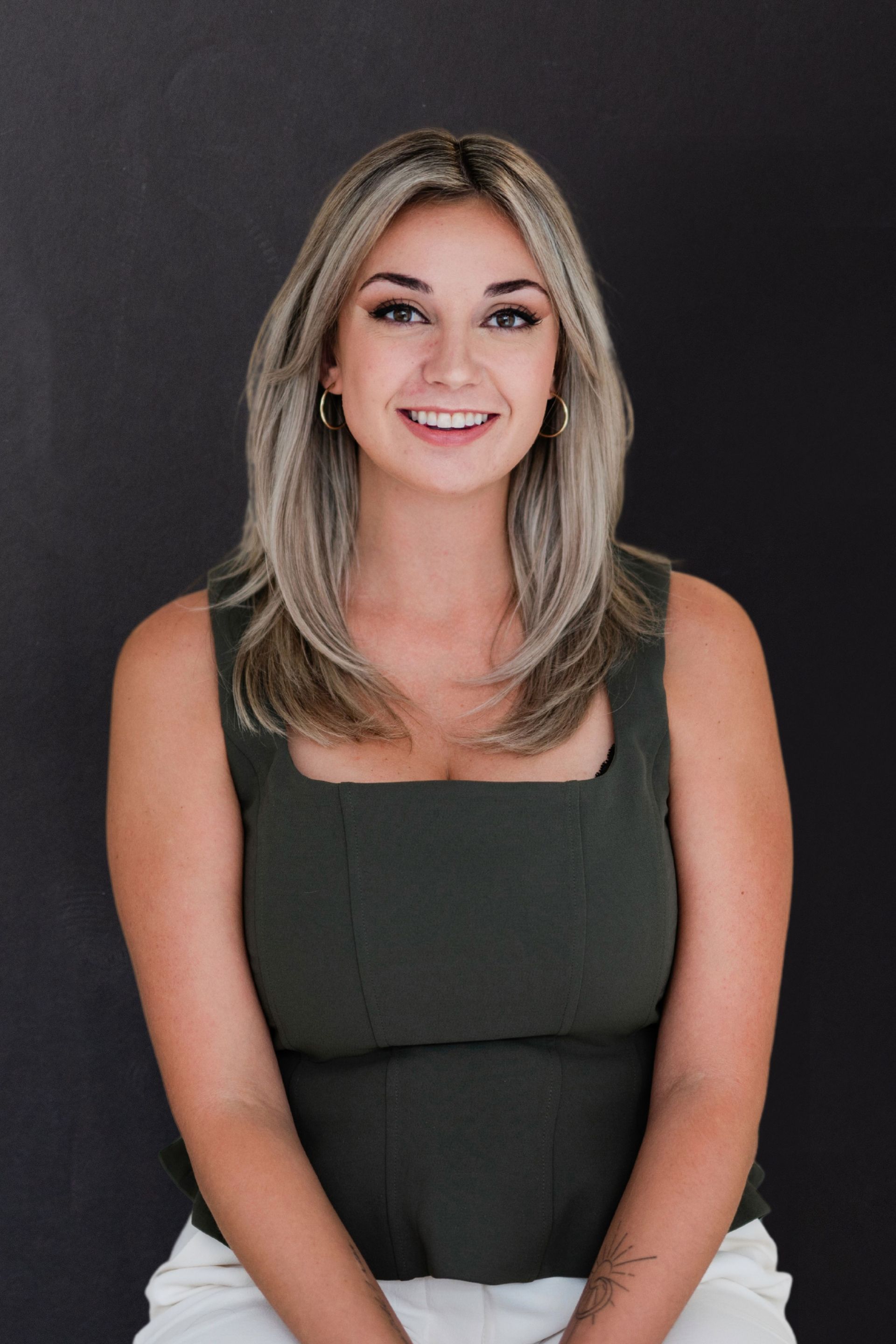 A woman in a green tank top and white shorts is smiling for the camera.